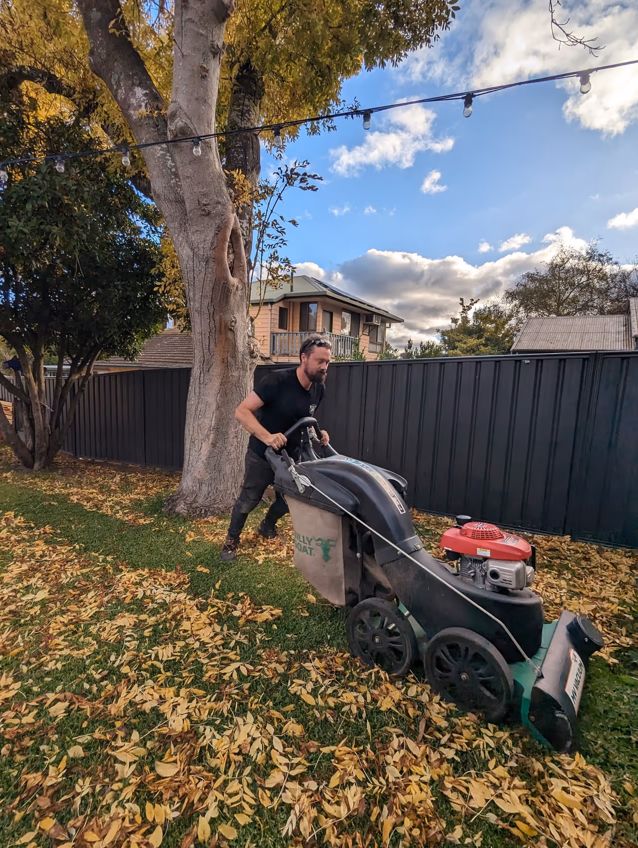 Landon vacuuming a thick blanket of autumn leaves from a strata lawn in Adelaide